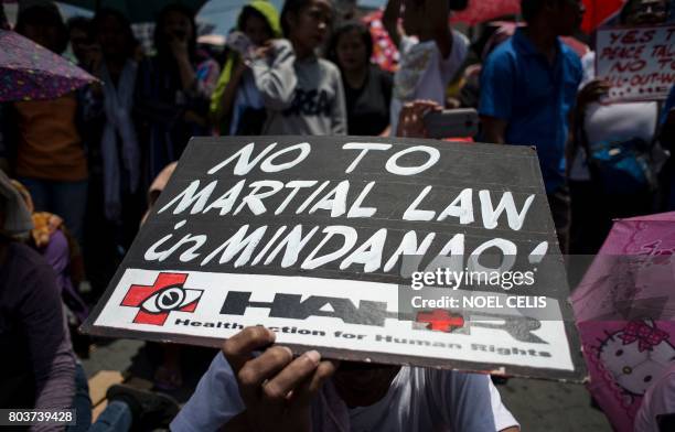 An activist hold an anti martial law banner during a protest at Malacanang palace in Manila on June 30, 2017. - Philippines President Rodrigo Duterte...