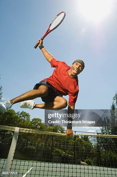 tennis player leaping over net - tennis man stock pictures, royalty-free photos & images