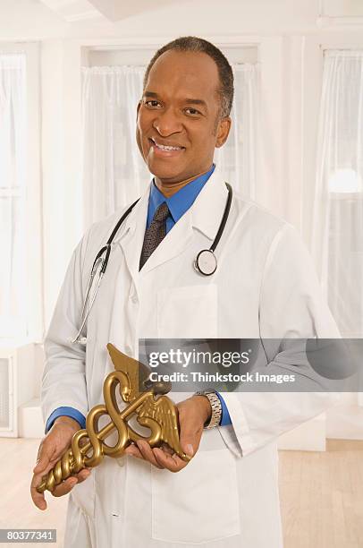doctor holding cadeuceus - gold caduceus stock-fotos und bilder
