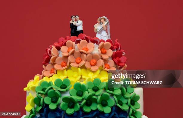 Wedding cake in rainbow colors and decorated with figurines of two women and two men is pictured in Berlin on June 30, 2017. - The German parliament...