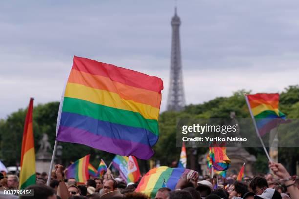Rainbow flag, commonly known as the gay pride flag or LGBT pride flag, is held up in front of an Eiffel tower during a rally ahead of the Paris Gay...