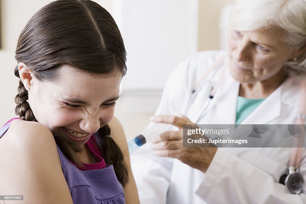 Doctor injecting preteen girl with needle