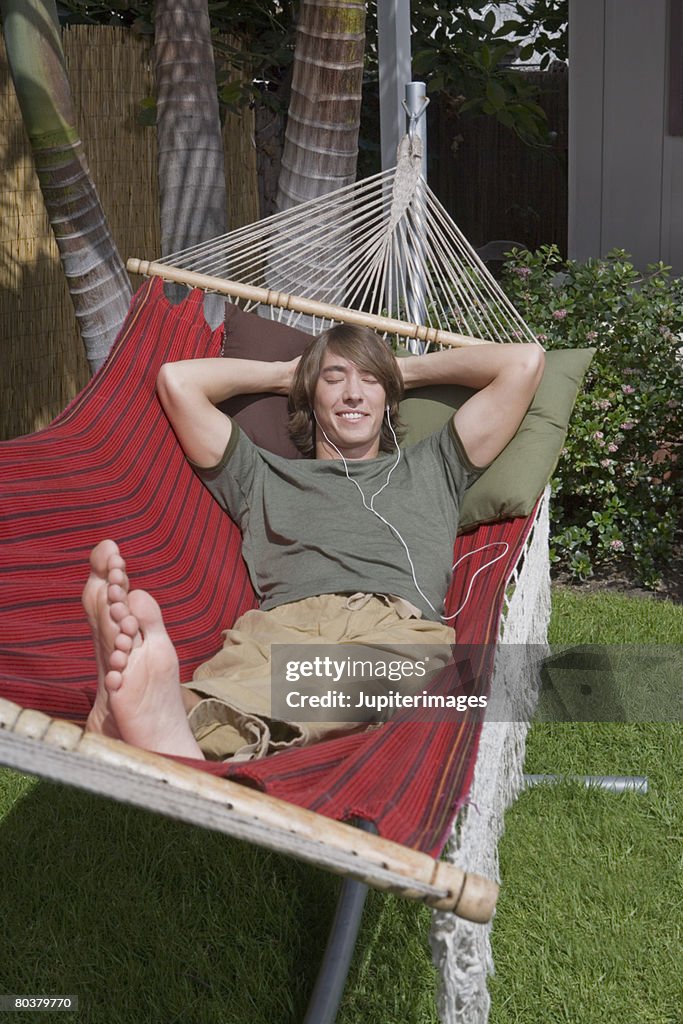 Man with earbuds relaxing in hammock