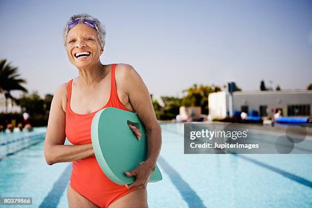 senior woman swimmer holding kickboard - old woman in swimsuit imagens e fotografias de stock