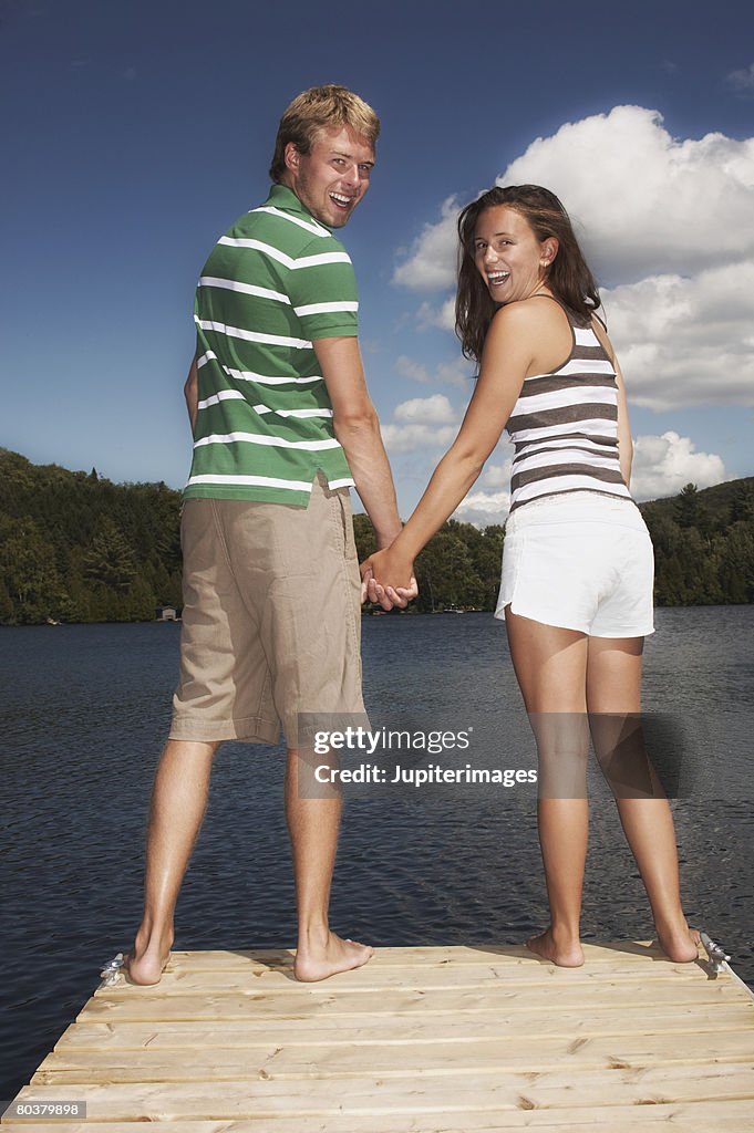 Teenage couple on dock holding hands