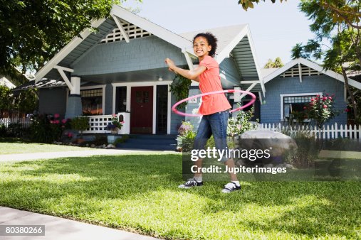 Girl with plastic ring toy on front lawn of house Girl with plastic ring toy on front lawn of house