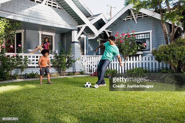 father and son playing soccer in front yard - family in front of home fotografías e imágenes de stock