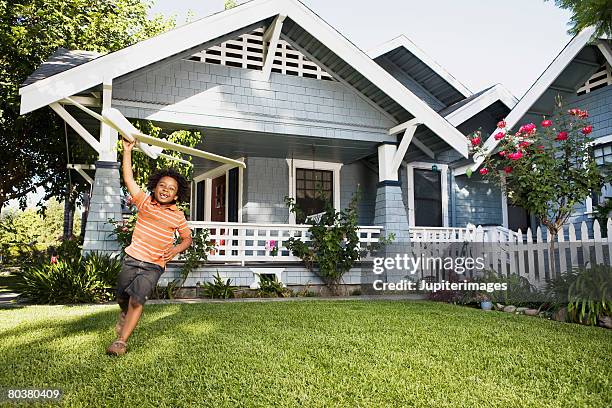 boy with toy airplane in front yard of house - children playing in yard stock-fotos und bilder