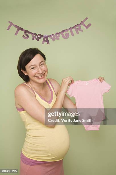 pregnant woman holding pink onesie - it's a girl stock pictures, royalty-free photos & images