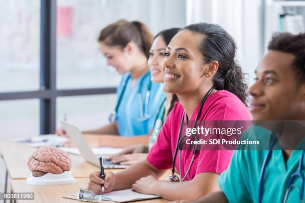 vrouwelijke nursing student glimlach met klasgenoten als ze tot professor luisteren - schooldokter stockfoto's en -beelden