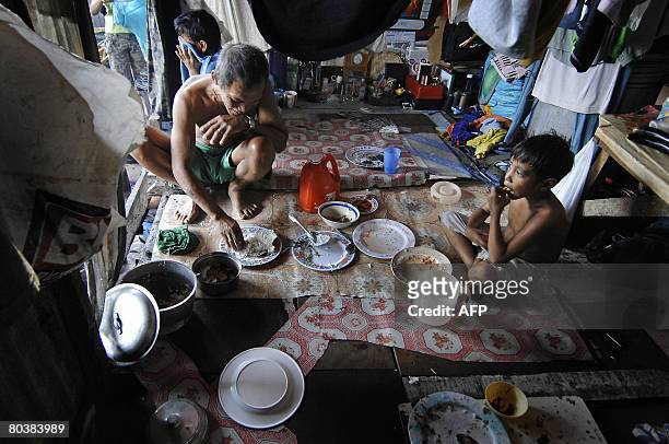 Angelito Cadiente eats a meal of rice with his youngest son in Manila on March 26, 2008. Angelito earns 100 pesos a day by washing vegetables at a...