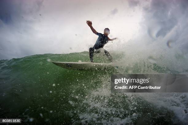 Valentin Verpoote rides a wave at the beach of Grand-Crohot near Lege-Cap-Ferret, on June 17, 2017. / AFP PHOTO / OLIVIER MORIN