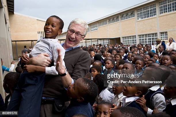 Paul O'Grady, the, Television personality, lifts a boy as he is welcomed by hundreds of children while visiting ZR Mahabane School on March 7, 2008...