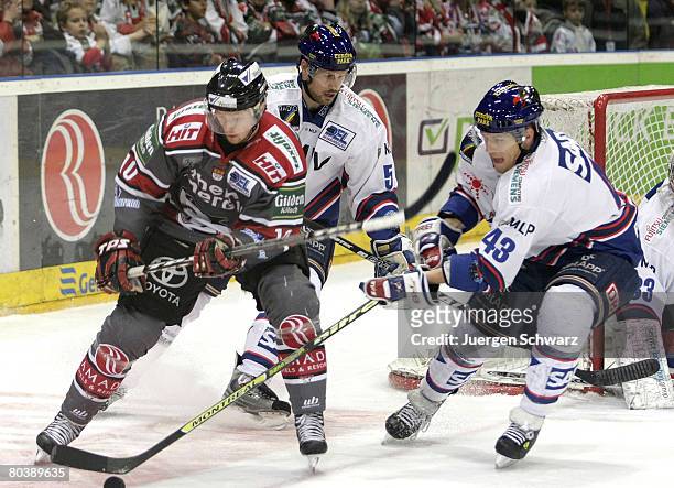 Alexej Dmitriev of Cologne and Felix Petermann of Mannheim fight for the puck in front of Dan McGills of Mannheim during the DEL Play-Off match...