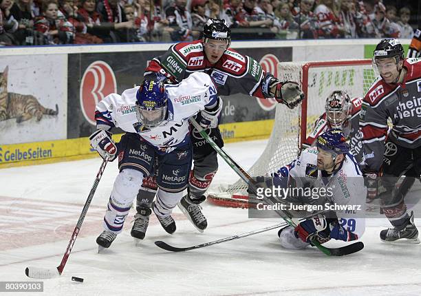 Jason Jaspers of Mannheim controls the puck near Moritz Mueller of Cologne and Jeff Shantz of Mannheim during the DEL Play-Off match between Koelner...