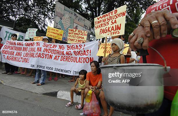 Protester holds an empty pot while others display placards during a protest in front of the Department of Agriculture office in Quezon city suburban...