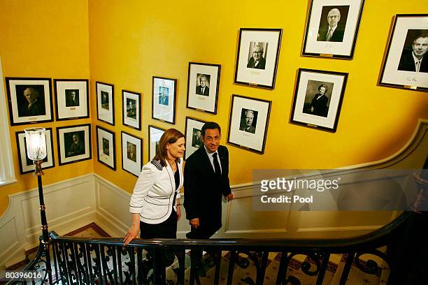 Sarah Brown, wife of British Prime Minister Gordon Brown, and French President Nicolas Sarkozy walk up the stairs past portraits of former British...