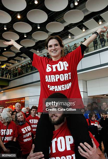 Pippa Tenant sits on the shoulders of Will Claus as part of a flash mob protest in Terminal 5 International Arrivals on March 27, 2008 in London,...