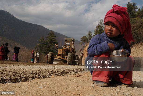 Nepalese child sits on the side of the road while her mother works on a road widening project March 25, 2008 in Thimphu, Bhutan. Tens of thousands of...