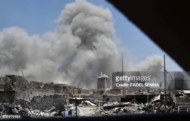 Smoke billows in the background behind the base of Mosul's destroyed ancient leaning minaret, known as the "Hadba" , in the Old City on June 30 after...