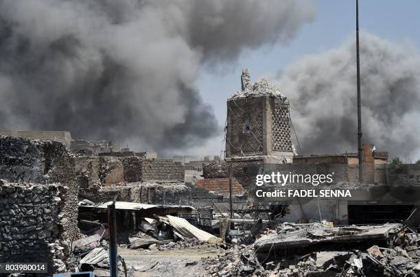 Smoke billows in the background behind the base of Mosul's destroyed ancient leaning minaret, known as the "Hadba" , in the Old City on June 30 after...
