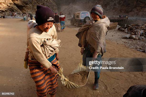 Nepali mothers carry their babies while hauling dirt working on a road widening project March 26, 2008 in Chuzom, Bhutan. Tens of thousands of...