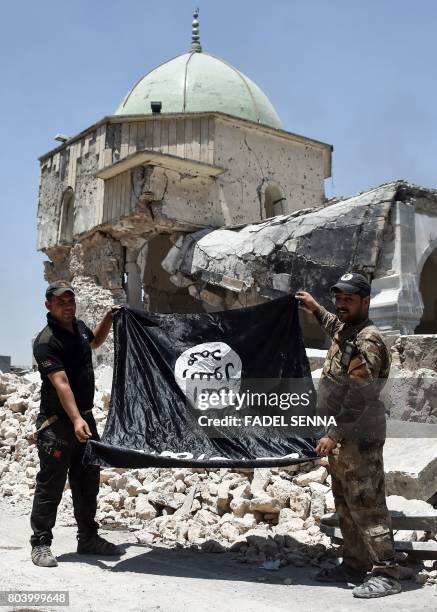 Members of the Iraqi Counter-Terrorism Service hold upside-down the black flag of the Islamic State group, outside the destroyed Al-Nuri Mosque in...