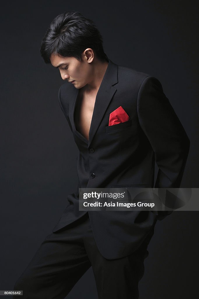 Young man in black suit looking down