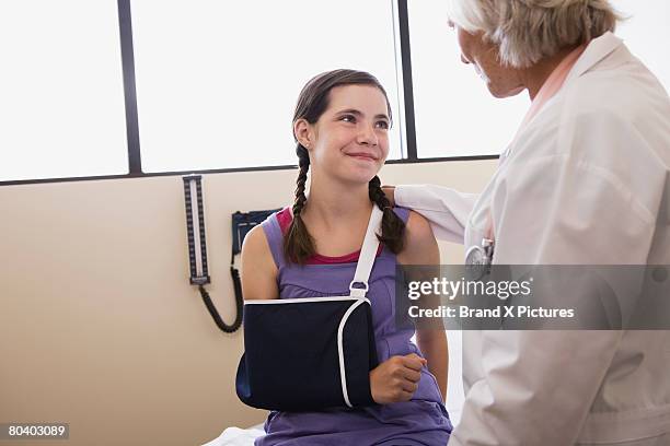 smiling preteen girl wearing sling with doctor - brandung bildbanksfoton och bilder