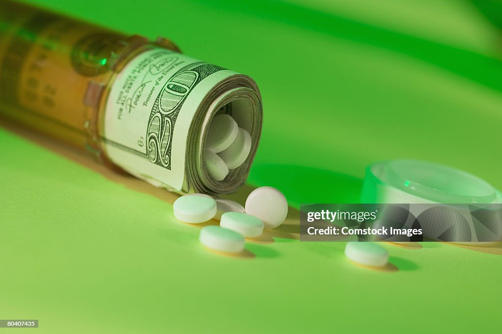 Dollar bills in pill bottle with medication