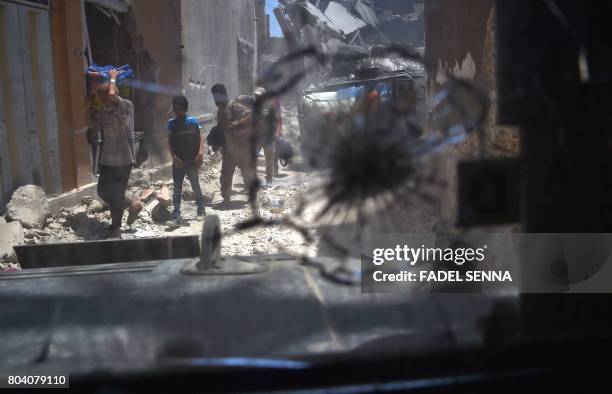 Picture taken on June 30, 2017 through a broken humvee windshield shows Iraqis evacuating the Old City of Mosul, as the Iraqi forces push their...