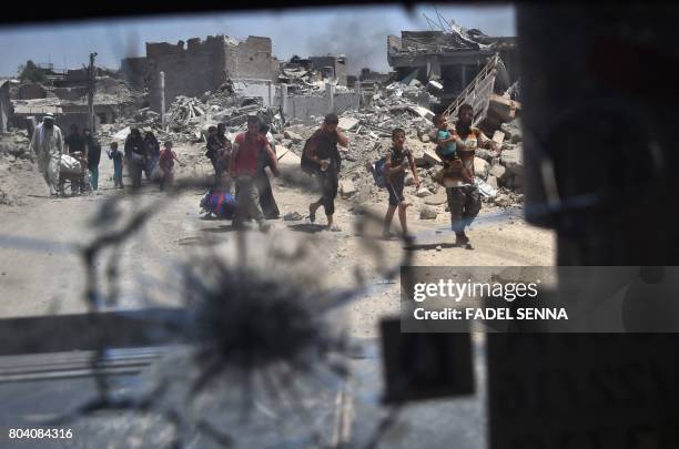 Picture taken on June 30, 2017 through a broken humvee windshield shows Iraqis evacuating the Old City of Mosul, as the Iraqi forces push their...