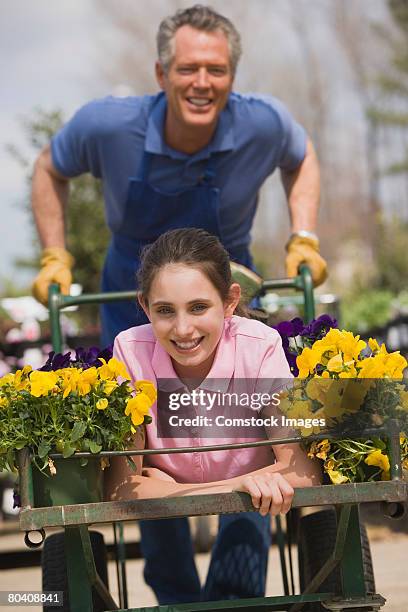 man pushing teenage girl in flower cart - man pushing cart fun play stock pictures, royalty-free photos & images