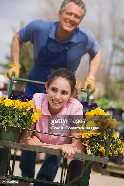 man pushing teenage girl in flower cart - man pushing cart fun play stock pictures, royalty-free photos & images