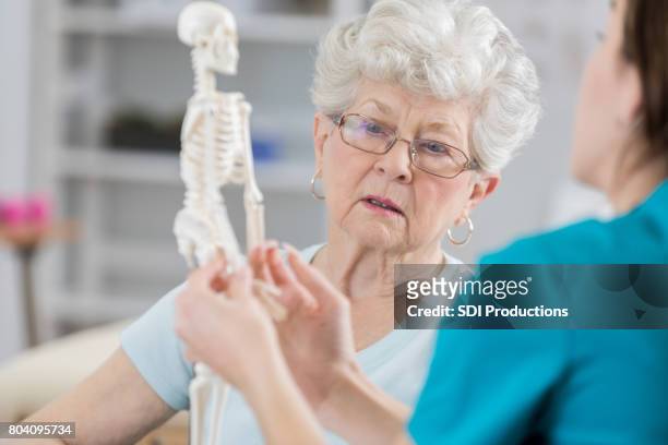 mulher sênior discute postura com fisioterapeuta - osteoporose - fotografias e filmes do acervo