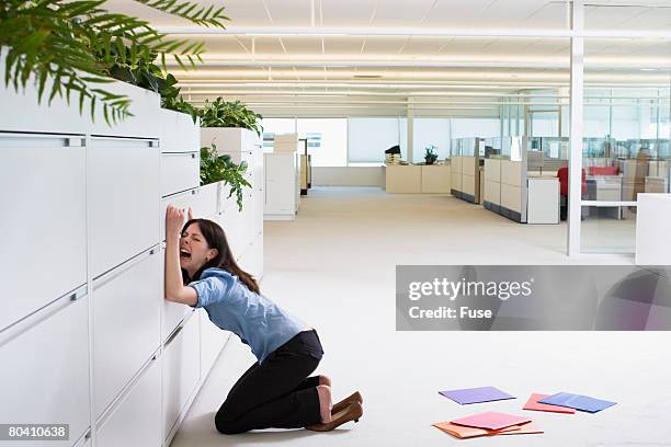 businesswoman crying against file cabinet - filing cabinet photos et images de collection