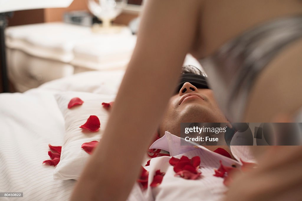 Woman Above Blindfolded Man on Bed
