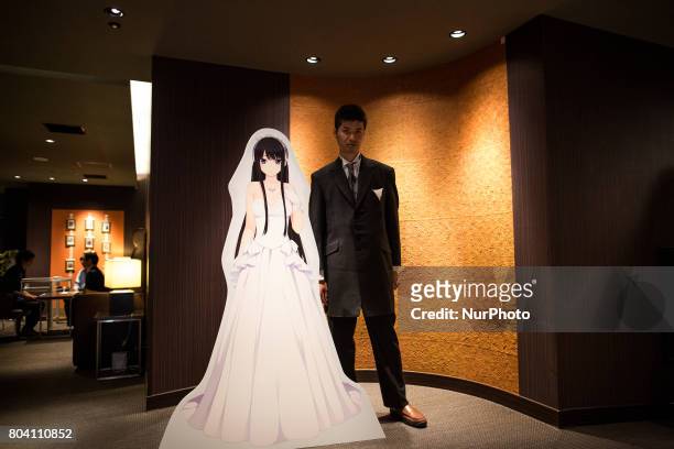 Anime fan posses with his new VR wife after a wedding ceremony in Tokyo, Japan on June 30, 2017. A marketing event by Japanese video game maker...