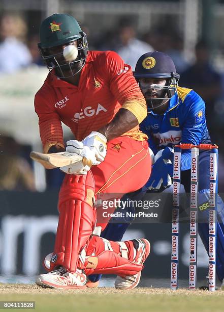 Zimbabwe's Solomon Mire plays a shot as Sri Lanka's Niorshan Dickwella looks on during the 1st ODI cricket match at the Galle International cricket...