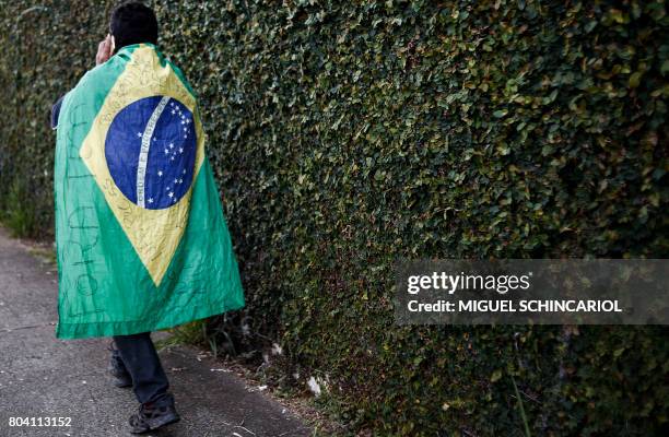 Member of the Roofless Movement wrapped in a Brazilian national flag walks outside Sao Paulo's Congonhas Airport during a protest against President...