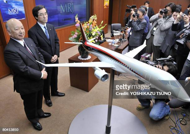 Japan's Mitsubishi Heavy Industries president Kazuo Tsukuda displays a scale model of the company's passenger jetliner "Mitsubishi Regional Jet " at...