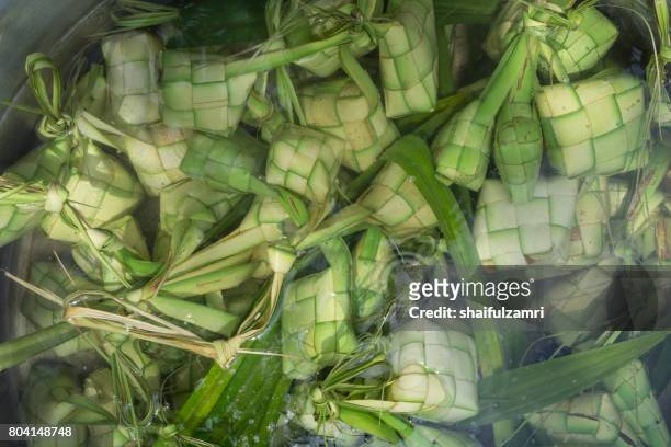 ketupat, kupat or tipat is a type of dumpling made from rice packed inside a diamond-shaped container of woven palm leaf pouch. it is commonly found in indonesia, malaysia, brunei and singapore. - ketupat stock pictures, royalty-free photos & images