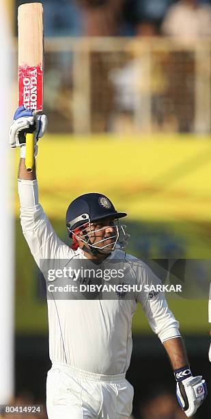Indian cricketer Virender Sehwag salutes the crowd as he runs between the wickets to complete his 300th run during the third day of the first Test...