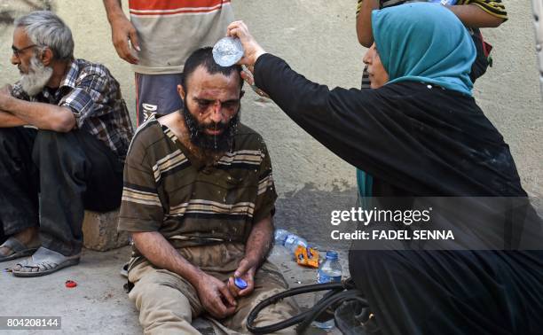 An Iraqi woman pours water over the head of an injured man during an evacuation from the Old City of Mosul on June 30 as Iraqi government forces...
