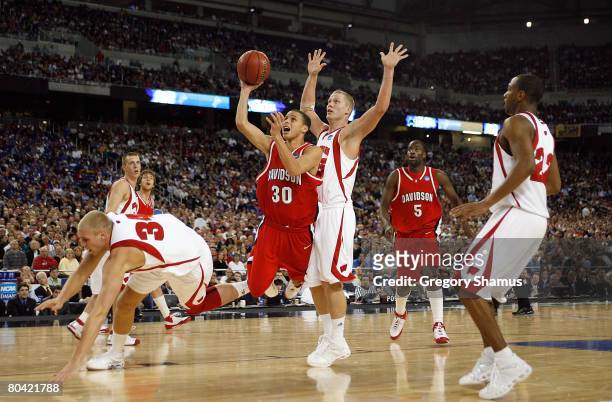 Stephen Curry of the Davidson Wildcats drives for a shot attempt against Greg Stiemsma and Joe Krabbenhoft of the Wisconsin Badgers during the...