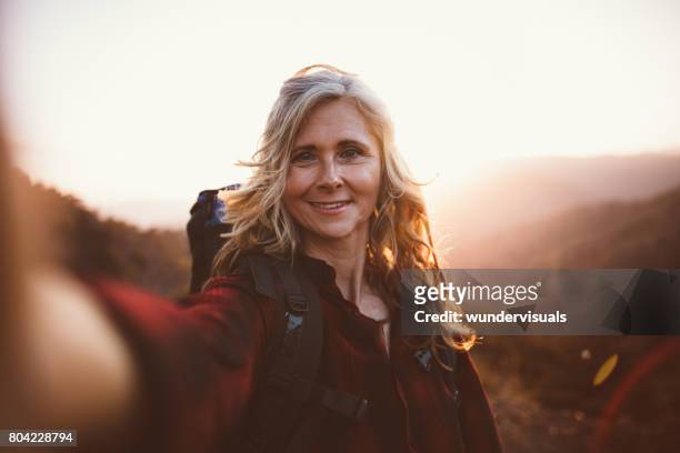 lycklig senior kvinna vandrare att ta en selfie på berget kant - backpacker woman bildbanksfoton och bilder
