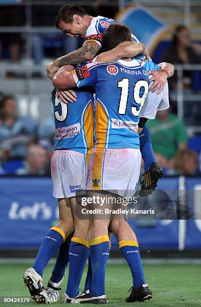 Jordan Atkins of the Titans celebrates with team mates Mat Rogers and James Stosic after scoring a try to seal the match during the round three NRL...