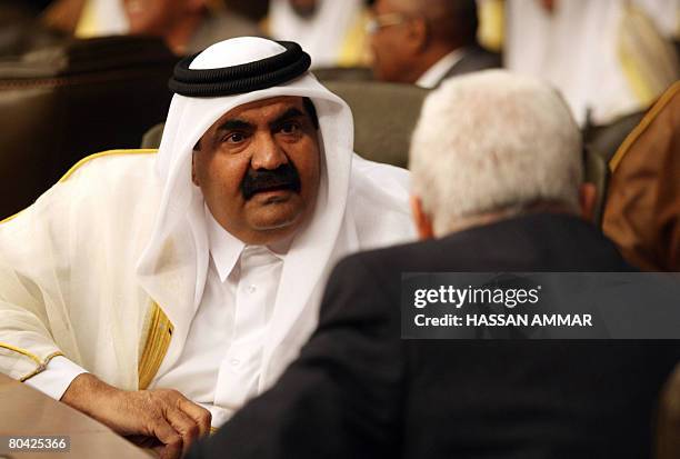 Qatar's Emir Sheikh Hamad bin Khalifa al-Thani speaks to Palestinian leader Mahmud Abbas at the opening session of the Arab Summit in Damascus on...