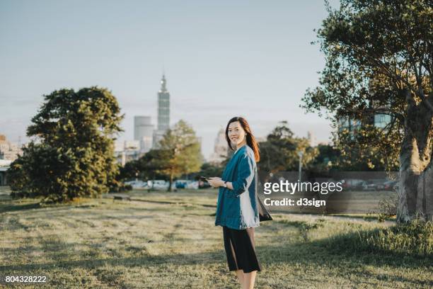 young asian lady reading text messages on smartphone outdoors - taipei landmark stock pictures, royalty-free photos & images