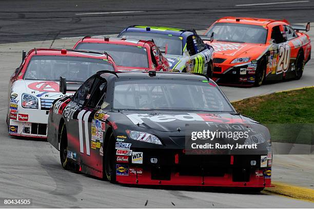 Denny Hamlin, driver of the FedEx Freight Toyota, leads a line of cars during the NASCAR Sprint Cup Series Goody's Cool Orange 500 at Martinsville...